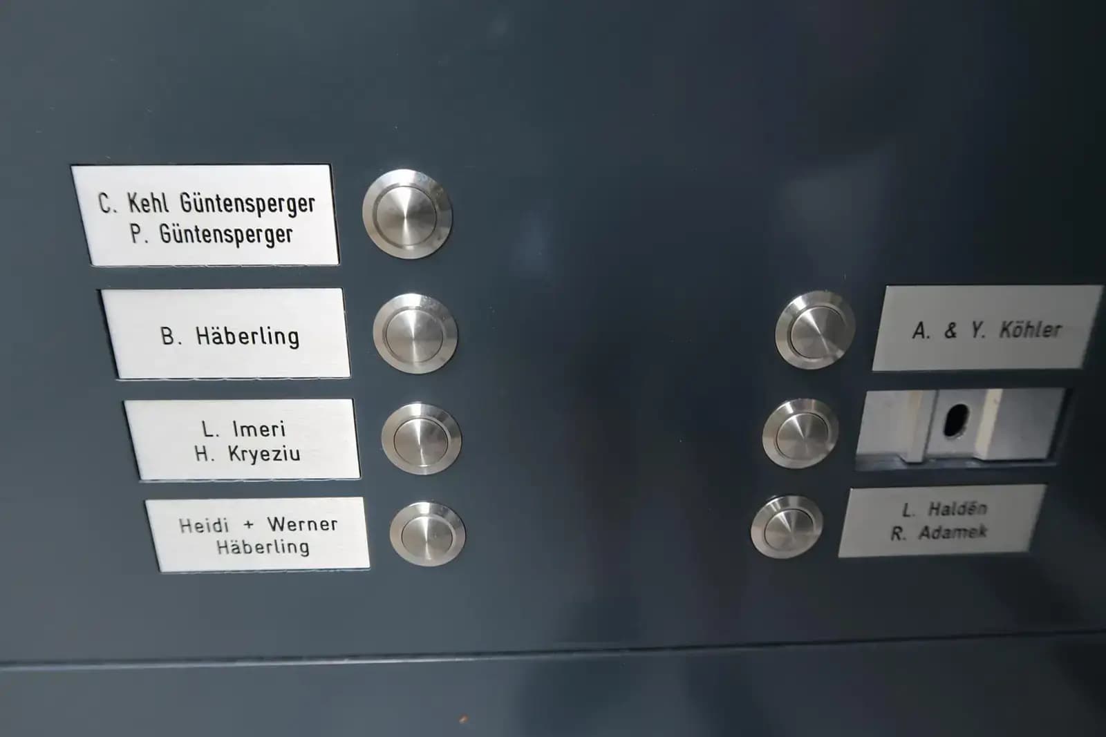Klingelanlage an dunkler Fassade mit weissen Namensschildern