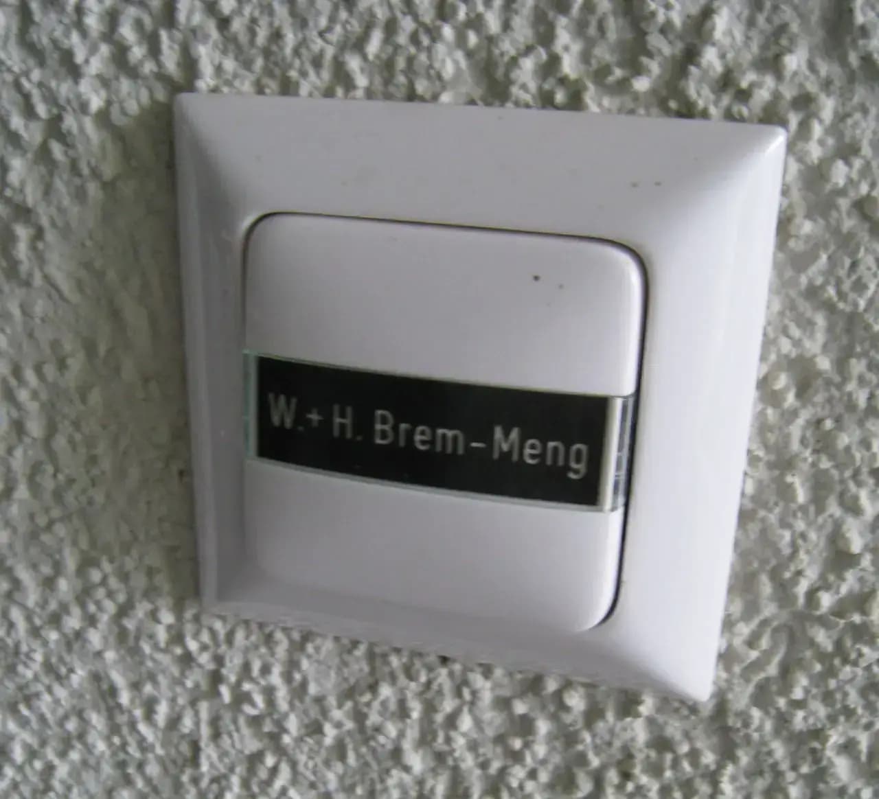 Wohnungsklingel mit schwarzem Namensschild im Halter